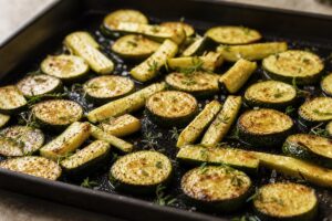 Courgettes au four bien dorées sur une plaque avec thym et huile d’olive