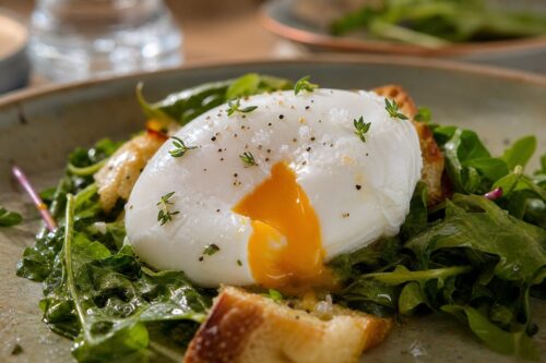 Œuf poché avec blanc net et jaune coulant sur une assiette de bistrot