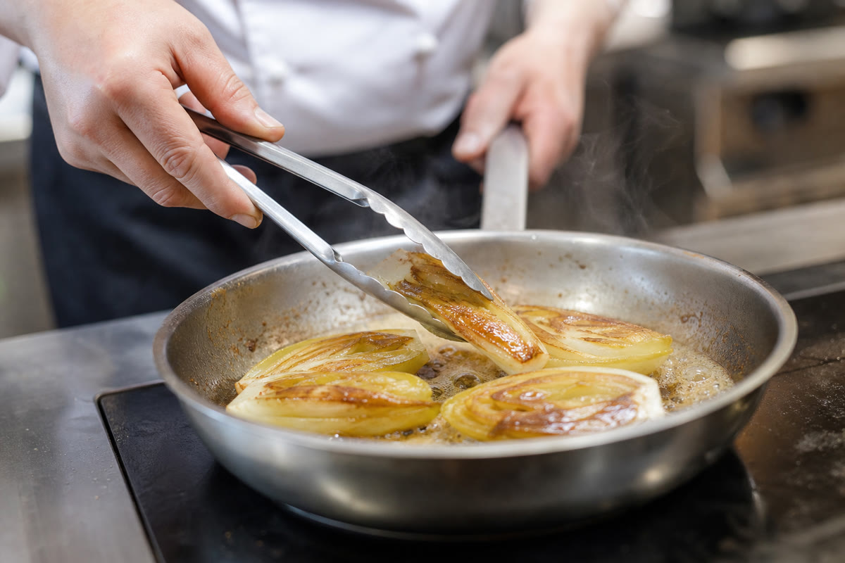 Endives braisées retournées dans une poêle avec du beurre mousseux