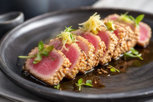 Tranches de tataki de thon au sésame avec cœur rosé sur assiette sombre