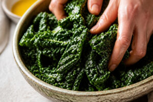 Feuilles de chou kale massées avec huile et sel dans un saladier
