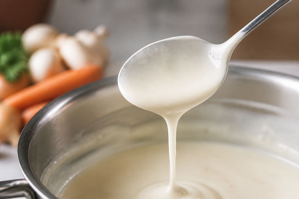 Une cuillère nappée d’une sauce blanche lisse pour vérifier la texture de la blanquette